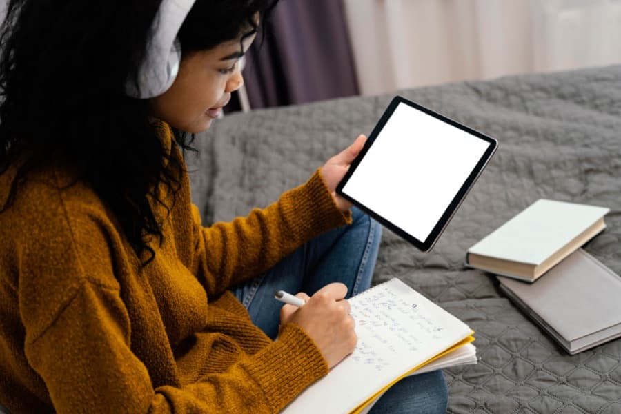 A student working on a tablet with a notebook